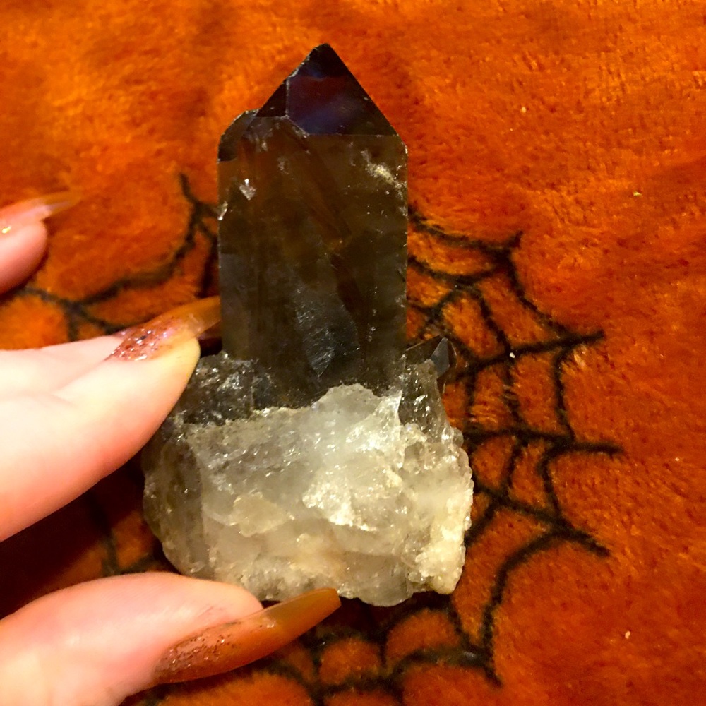 A Smokey quartz point, small size, color is brownish to blackish hue.